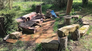 Un jardin avec des allées pavées de pierres, une construction en briques et des rochers éparpillés.