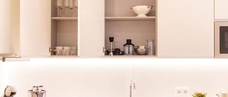 A modern kitchen with white cabinets, a stainless steel sink, and various kitchen appliances.