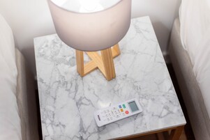 A white marble bedside table with a white lamp and a digital control panel.