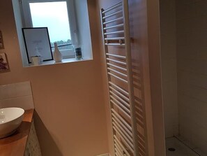 Une salle de bain avec un lavabo blanc, un miroir et un porte-serviettes.