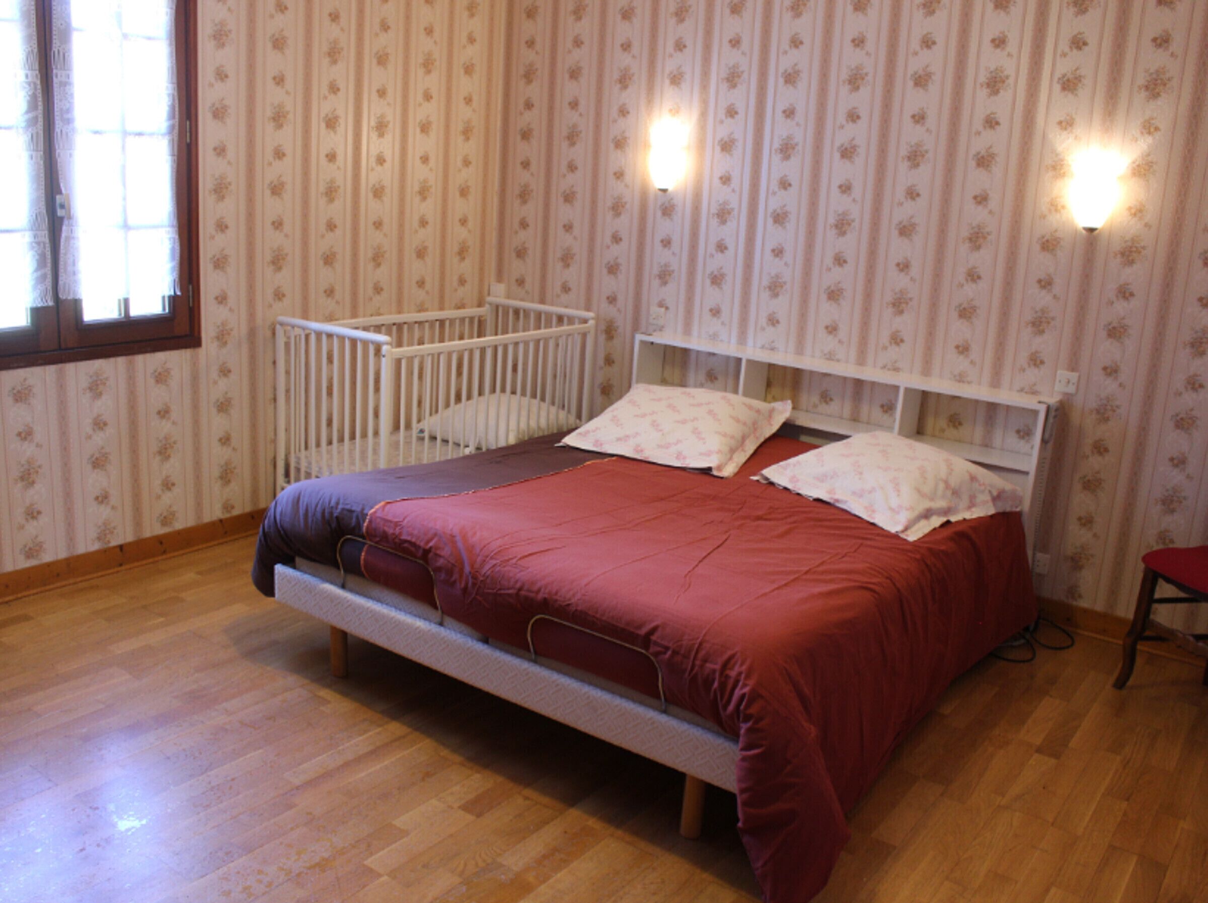 A bedroom with a single bed, a crib, and a window with curtains.