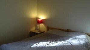 Ett sovrum med en säng, ett nattduksbord och en lampa.
