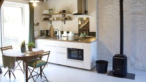 A modern kitchen with white cabinetry, a wooden dining table with chairs, and a black stove.