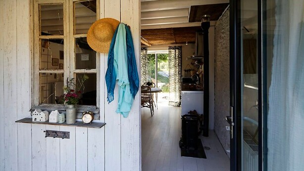 A rustic wooden exterior with a window, a hat, and a blue cloth hanging on the wall.