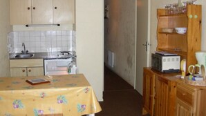 Een kleine keuken met een spoelbak, fornuis en houten keukenkastjes.