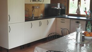 Une cuisine avec des meubles blancs, un plan de travail noir et une table à manger avec des chaises.