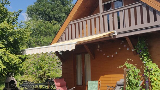 Une cabane en bois dotée d’un balcon, d’un espace extérieur aménagé pour s’asseoir et d’un jardin.