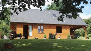 Une maison en bois avec un toit en pente, une véranda et une pelouse.