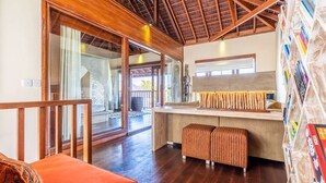 A spacious room with a wooden ceiling, a large window, and a bookshelf filled with books. - Pristine Villa Yuyu Balian (Tabanan)