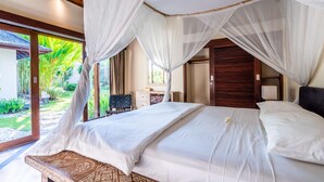 A bedroom with a canopy bed, a view of the garden, and a wooden headboard. - Pristine Villa Yuyu Balian (Tabanan)