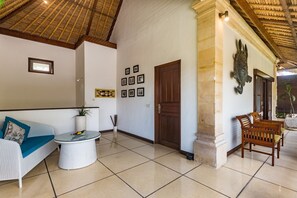 A spacious room with a high ceiling, a wooden door, and a wall adorned with framed pictures. - Villa Krisna (Seminyak)