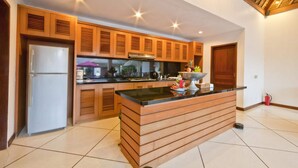 Eine moderne Küche mit Holzschränken, einer zentralen Kochinsel und einem Edelstahl-Kühlschrank.