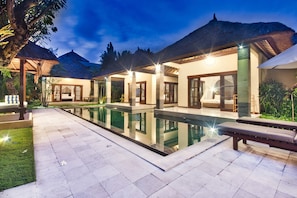 A modern resort with a swimming pool, thatched-roof structures, and well-lit outdoor areas. - Villa Cinta (Seminyak)