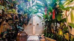 A tropical garden with a stone pathway leading to a door, surrounded by lush greenery and large decorative pots. - Villa Kebun (Seminyak)