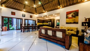 A spacious living area with a high ceiling, a dining area, and a kitchen. - Villa Kebun (Seminyak)