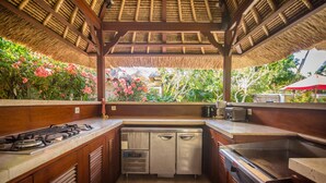 A compact kitchen with a gas stove, a built-in dishwasher, and a stainless steel sink. - Villa Jaclan (Seminyak)
