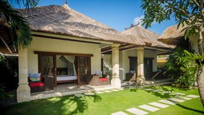 A resort with thatched-roof cottages, a well-maintained lawn, and a stone pathway. - Villa Jaclan (Seminyak)