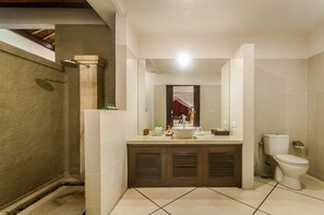Un baño con lavamanos grande, espejo y retrete.