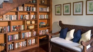 A library with wooden bookshelves, a wooden staircase, and a bench with cushions.