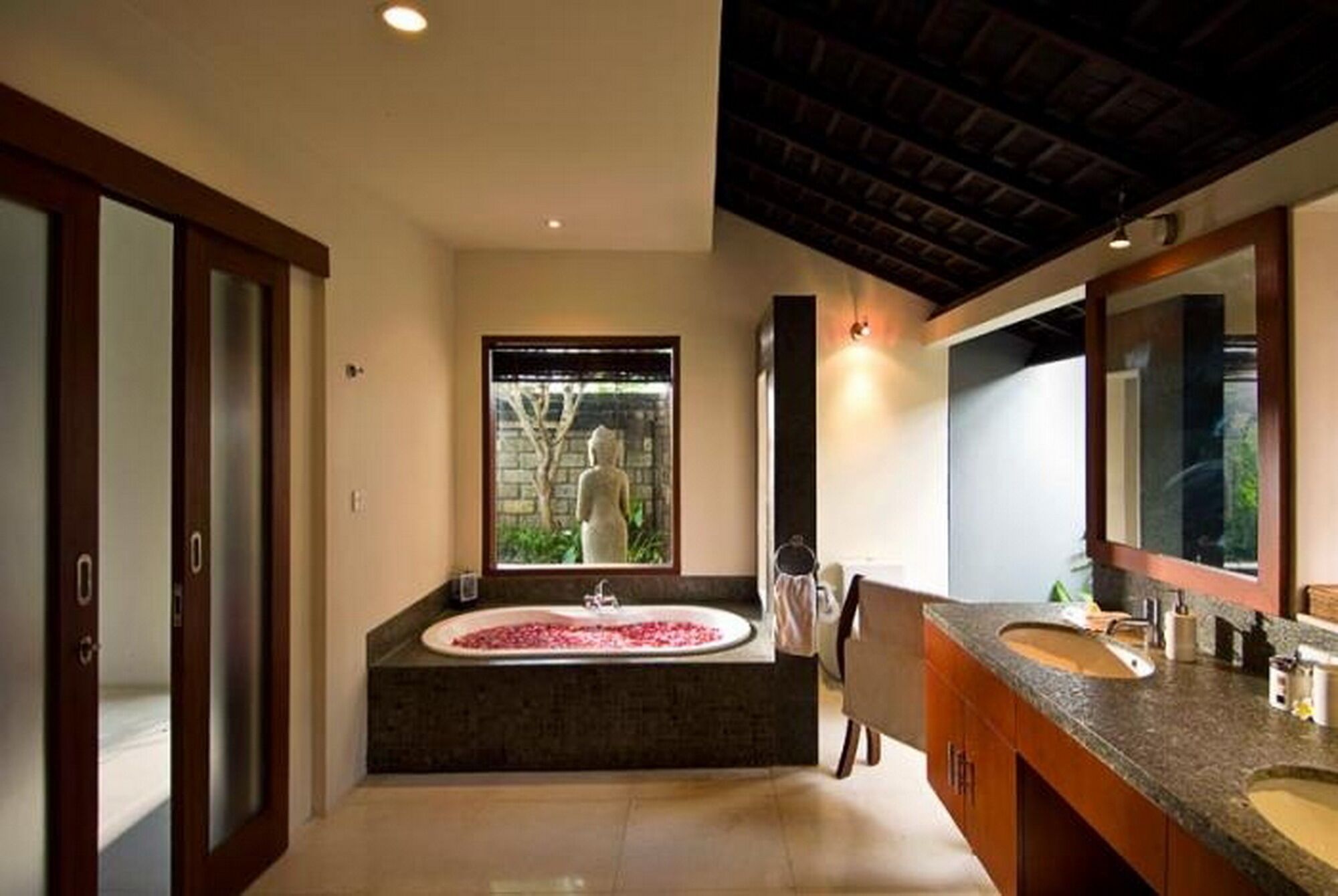 A modern bathroom with a large bathtub, a separate shower area, and a vanity with a mirror.