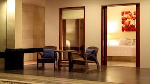 A hotel room with a bed, two wicker chairs, a small table, and a mirror. - Villa Padar (Kerobokan)