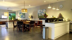 A modern kitchen with a central island, pendant lighting, and a dining area with chairs. - Villa Padar (Kerobokan)
