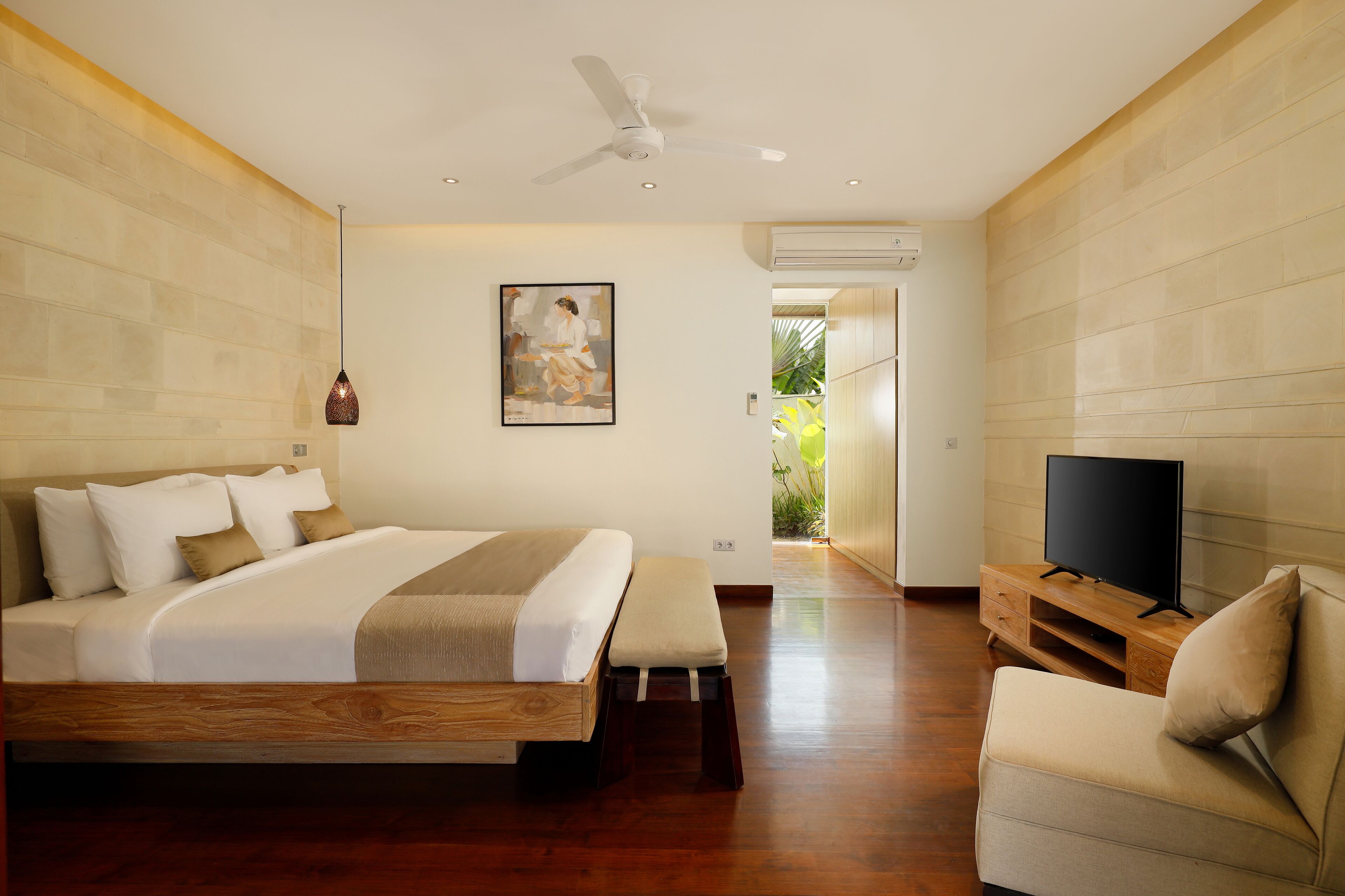 A hotel room with a bed, a TV, a chair, and a painting on the wall.