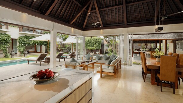 Un amplio espacio interior con piscina, sillones de descanso y zona de comedor.