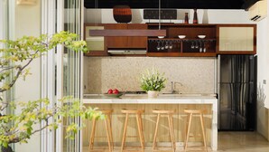 Una cocina moderna con taburetes de madera, salpicadero de azulejos y refrigerador de acero inoxidable.
