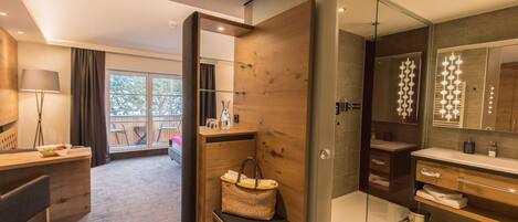 Un baño moderno con ducha de vidrio, tocador con espejo y una zona de estar con una cesta.