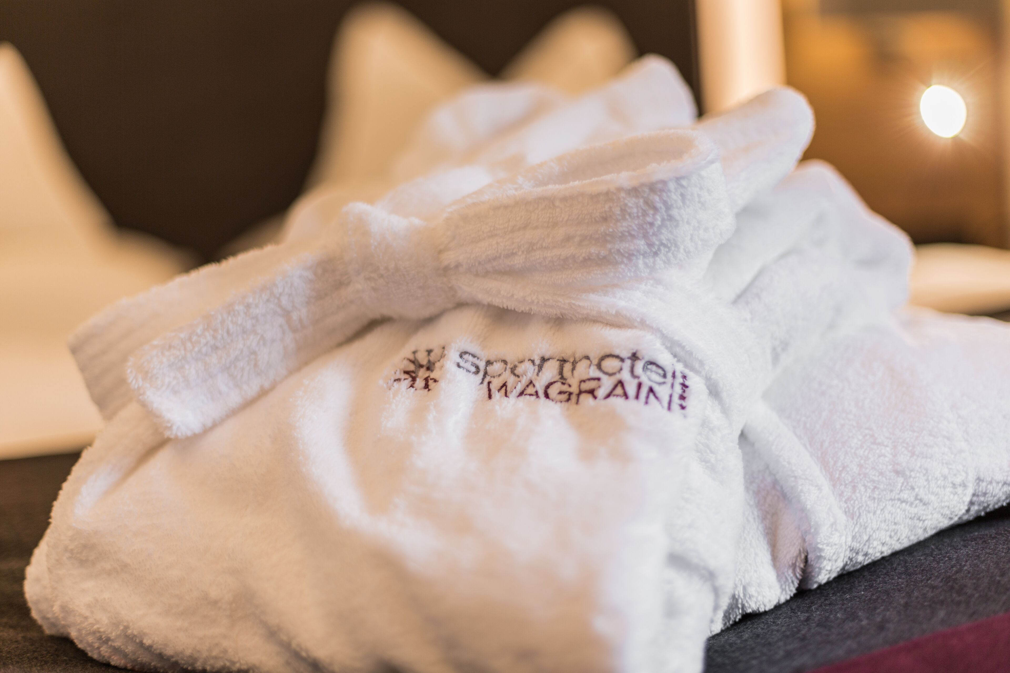 A white towel with embroidered text on a hotel room surface.