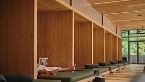 A modern spa area with wooden paneling, green cushioned seating, and a view of greenery through large windows. - Sporthotel Wagrain (Wagrain)