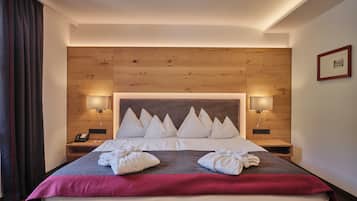 A hotel room with a large bed, wooden headboard, two bedside lamps, and a framed picture on the wall.