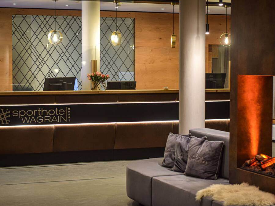 A reception area with a modern design, featuring a reception desk, a sofa, and a fireplace.