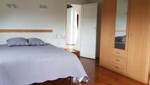 Een slaapkamer met een bed, een houten garderobe en een nachtkastje.
