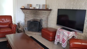 Een woonkamer met een open haard, lederen meubels, een flatscreen televisie en een tafel met een kantelaar.