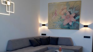 A modern living room with a grey sofa, a round coffee table, and a painting on the wall. - AR apartment (Πλατανίδια)
