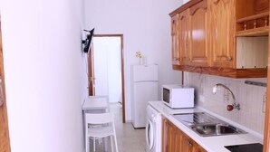 A compact kitchen with a washing machine, a microwave, and wooden cabinets. - Mele Sky Beach, BEACH APARTMENT, sea views, terrace and sun (Lomo Quiebre)