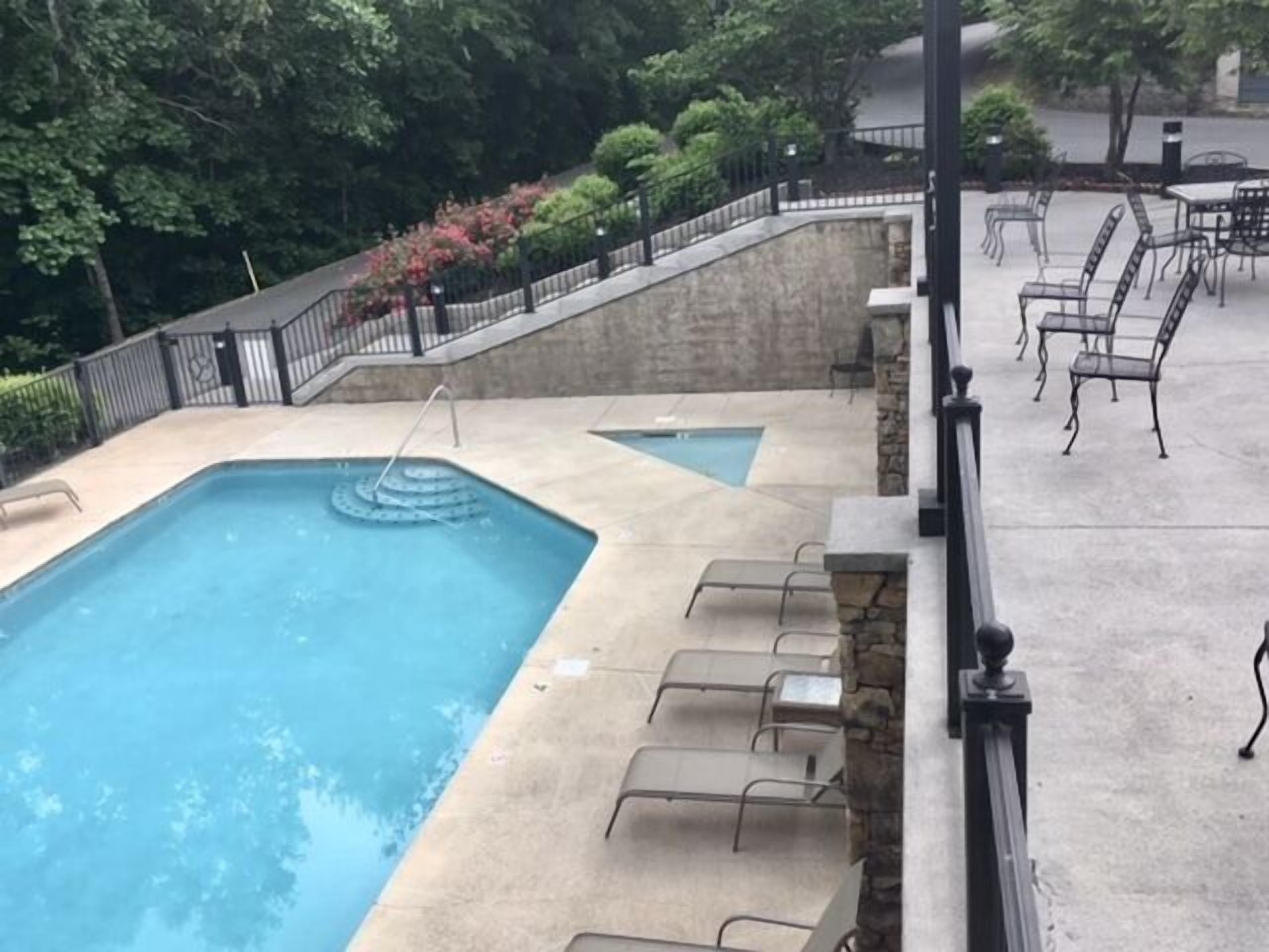 A swimming pool with a stone deck and lounge chairs.