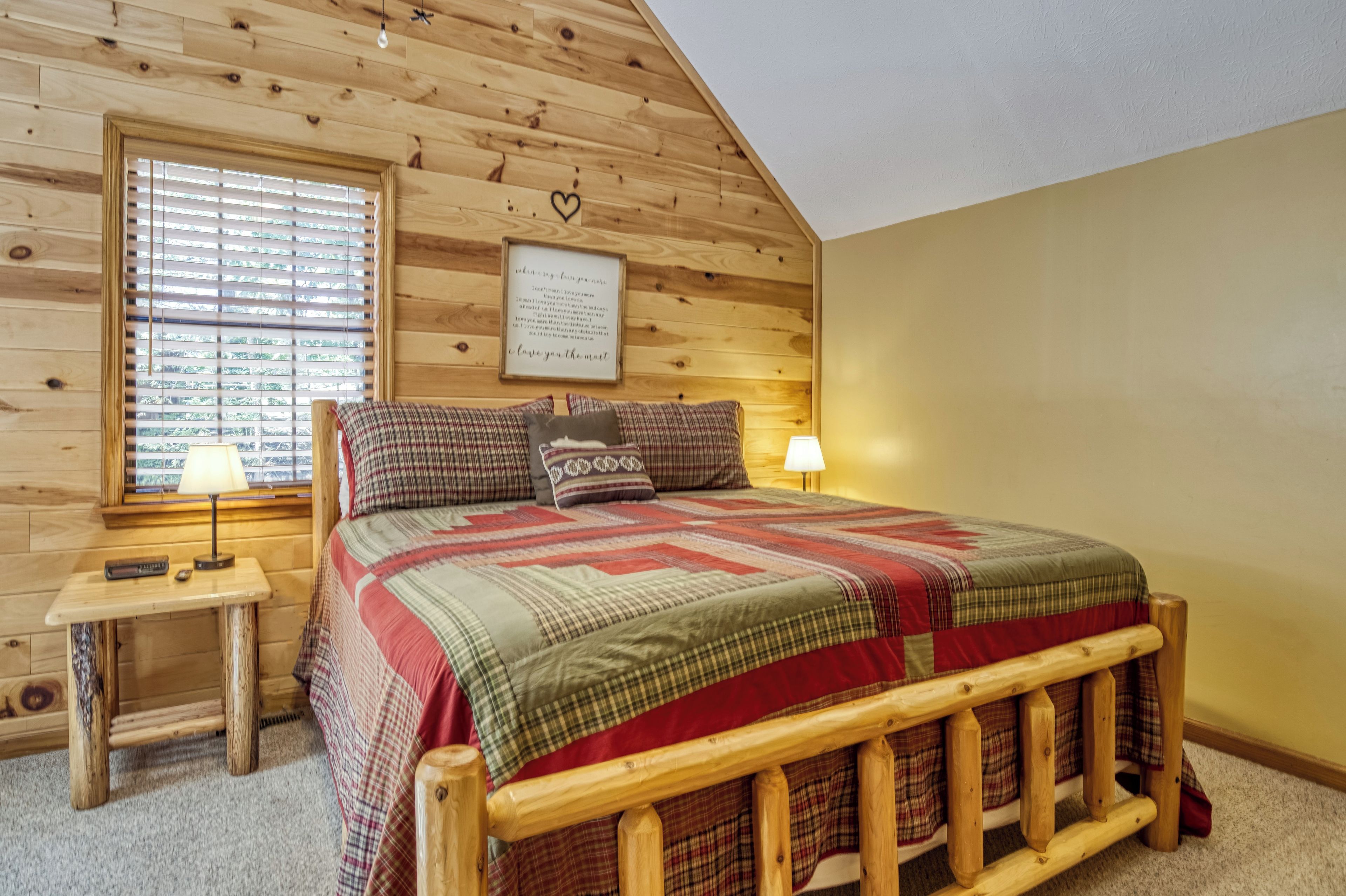 Un dormitorio acogedor con una cama litera de madera, una mesita de noche con lámpara y una ventana con persianas.