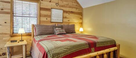 Un dormitorio acogedor con una cama litera de madera, una mesita de noche con lámpara y una ventana con persianas.