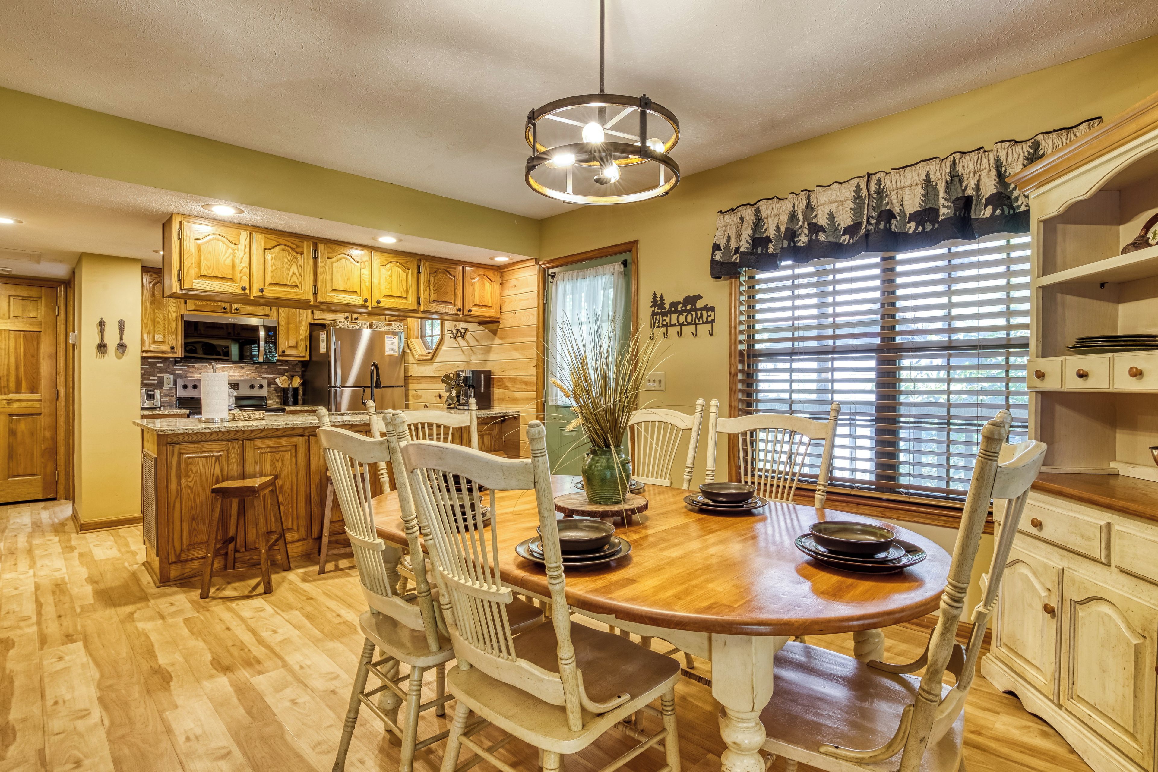 Una cocina con armarios de madera, una isla central y un comedor con mesa y sillas de madera.