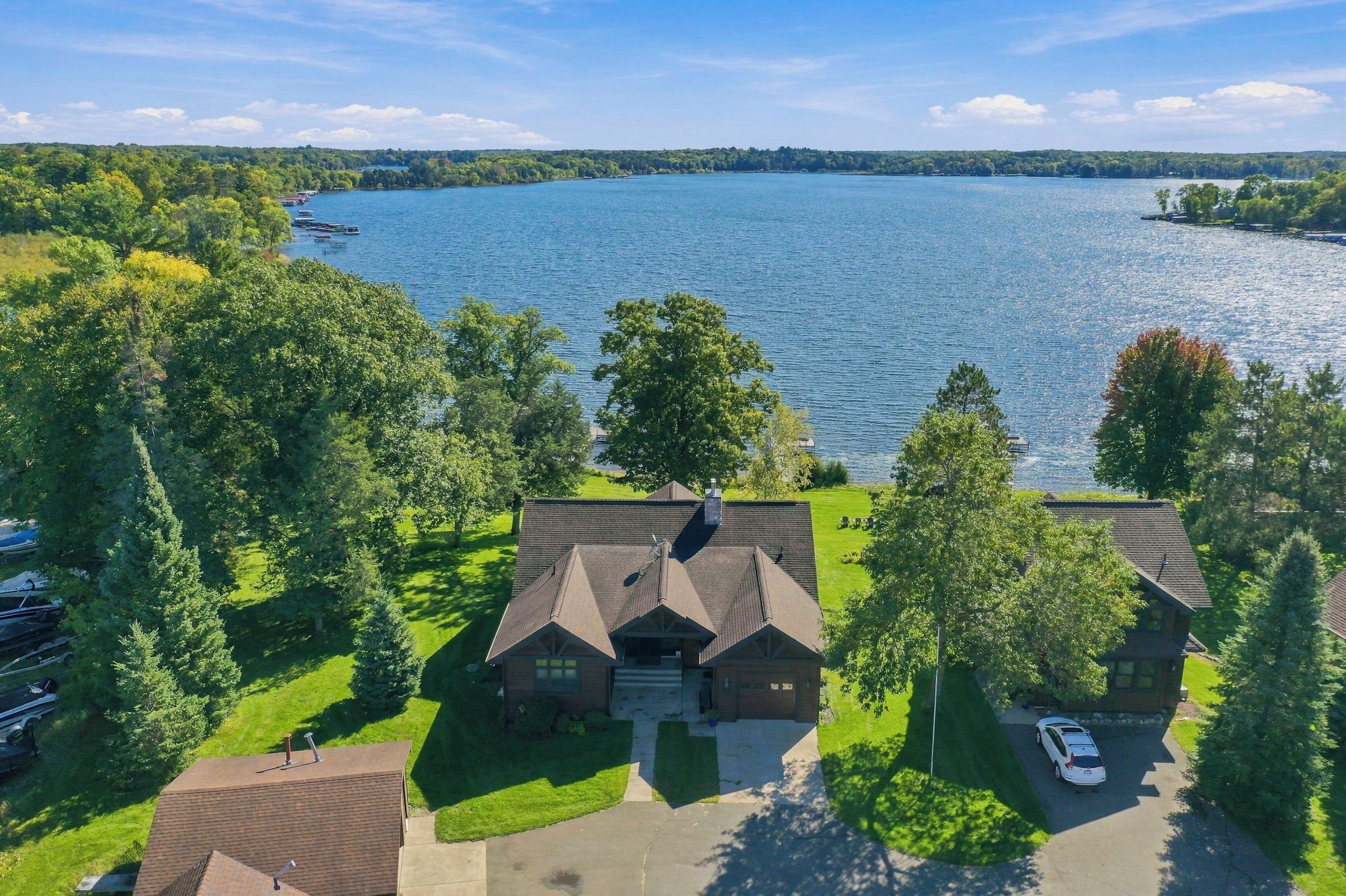 Une propriété au bord du lac, comprenant une grande maison, un quai et des bateaux.