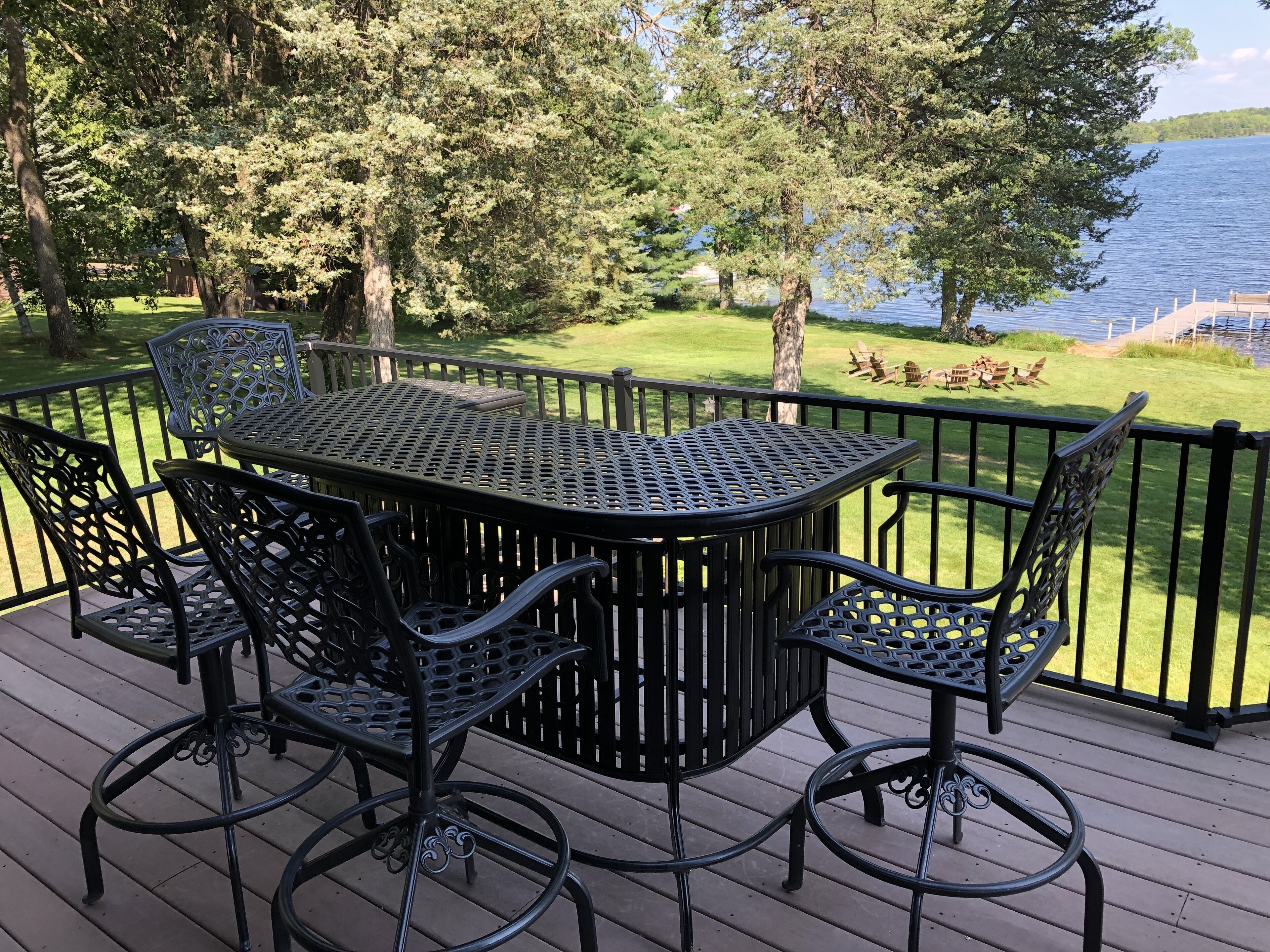 Une terrasse avec une table et des chaises, donnant sur une pelouse et un plan d’eau.