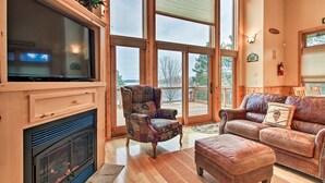 A spacious living room with a fireplace, large windows, and a cozy seating area. - Bay Lake Cabin w/200ft of Lakefront, fun deck, private dock + woodfire sauna!  (Deerwood)