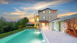 Une maison moderne dotée d’une piscine, de murs en pierre et d’une pelouse bien entretenue.