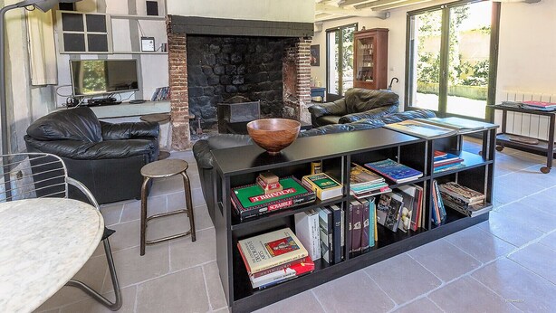 Un salon chaleureux avec une cheminée, des meubles en cuir et une bibliothèque remplie de livres.