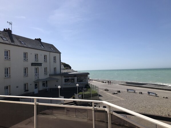 A hotel with a restaurant and bar, overlooking a pebbled beach and the sea.