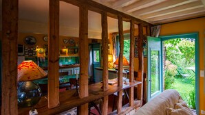 Habitació rústica amb bigues de fusta, una taula de menjador i vista a un jardí a través d'una finestra.