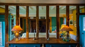 Habitació amb taula de fusta, dues làmpades i un llit amb una paret verda i una finestra.